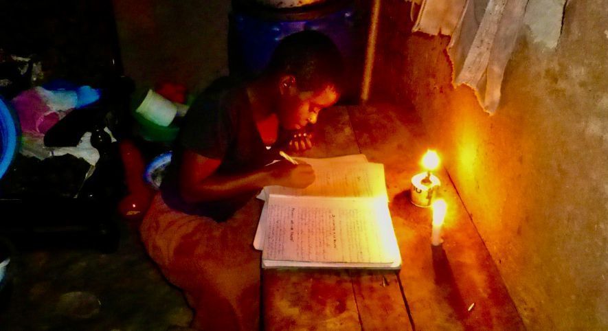Girl doing her homework with candles for her light.