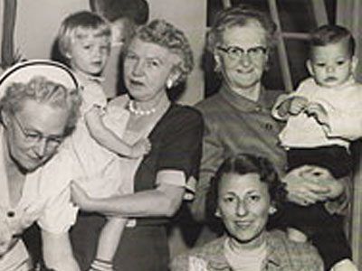 A black and white photo of nurses holding infants. 