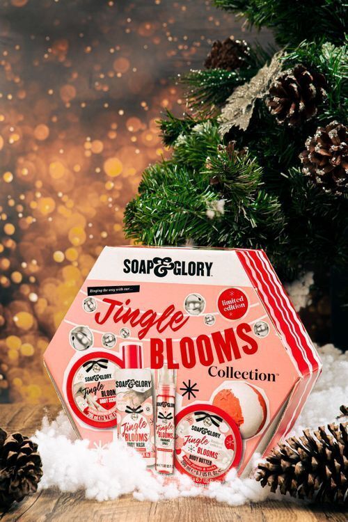 Soap & Glory's pink hexagonal Jingle Blooms holiday gift set under a Christmas tree, illustrating festive packaging design trends for beauty brands.