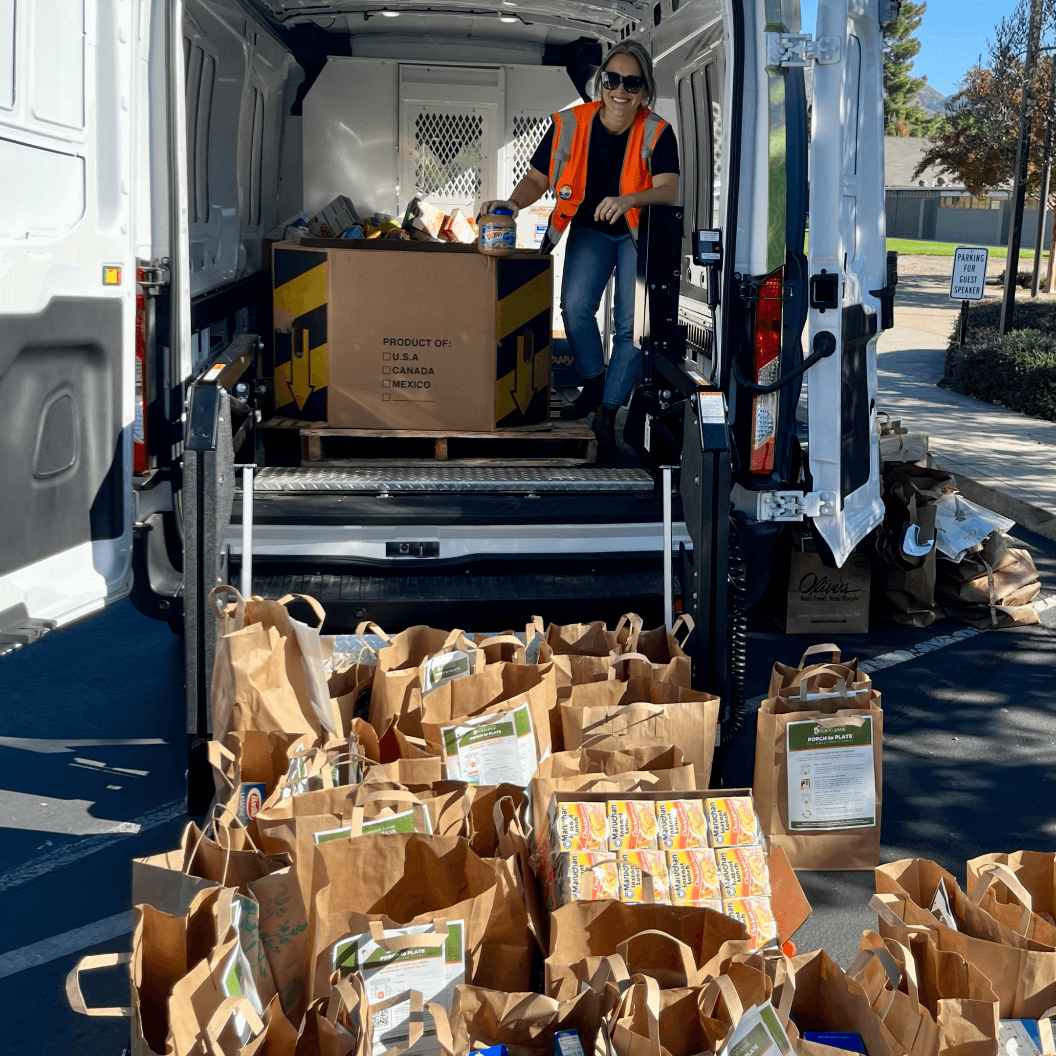 Photo of a young boy in the hatchback of the car carrying out bags of food to donate