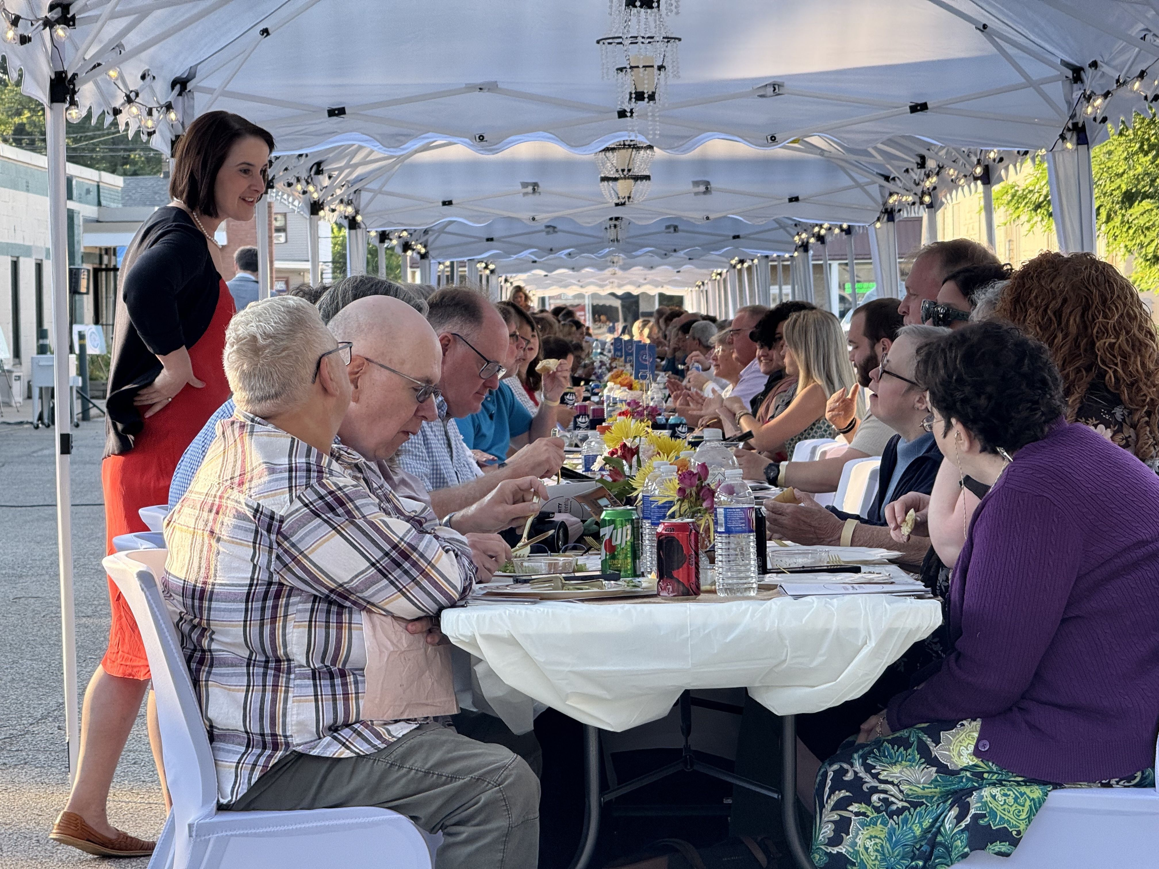 A large group of people sharing a meal outdoors.
