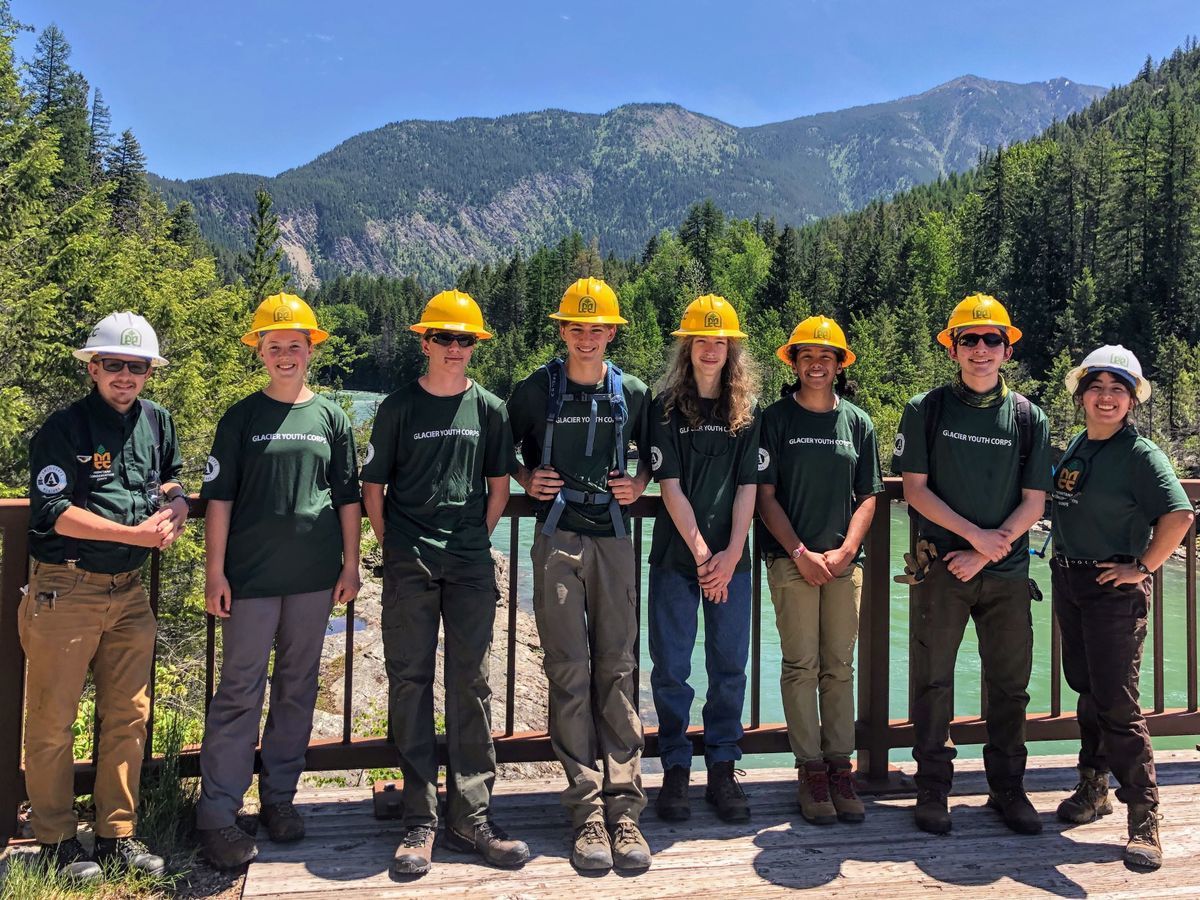 [Image Description: Six MCC youth members and two leaders pose together, smiling, wearing Glacier Youth Corps t shirts and their hard hats.]