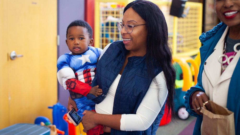 Mom and young son together trick-or-treating inside for Halloween fun