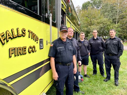 5 Firemen stand beside their day-glow Yellow Fire Truck