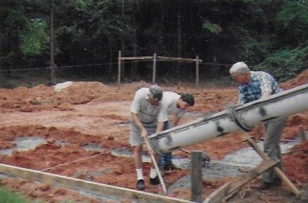 Three male volunteers work to pour foundation. 