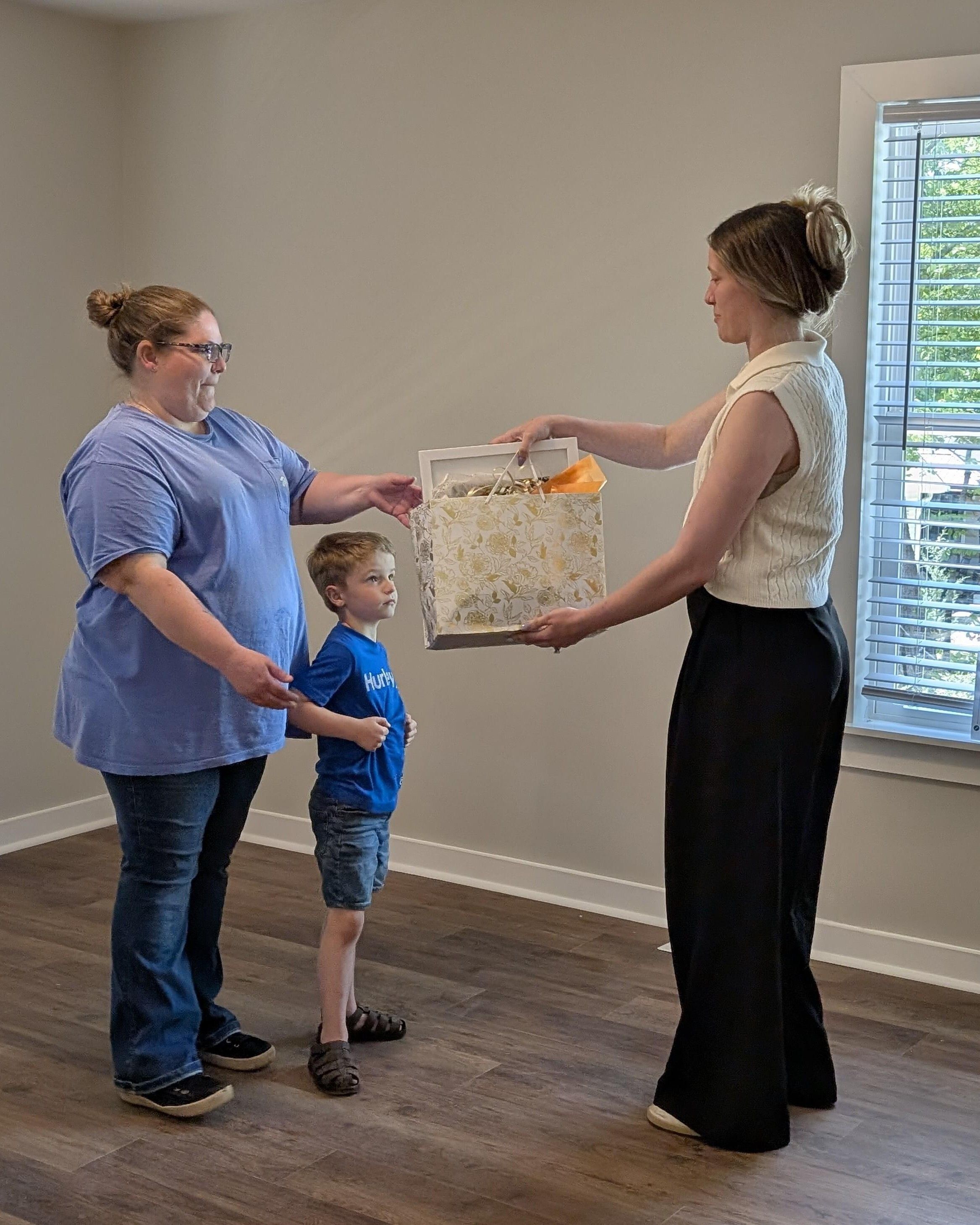 Homeowner partner family receiving custom art piece in gift bag from Clemson Art Department student