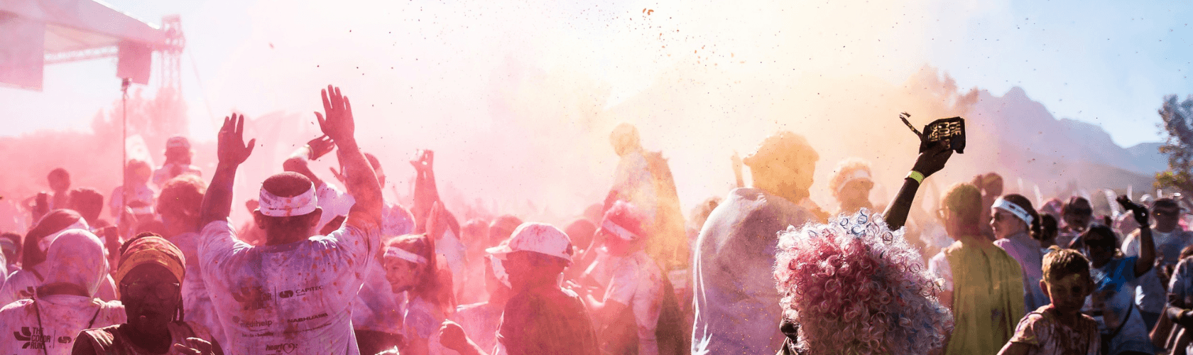 4 girls running through the Hope for Minds Color Run finish line with clouds of color surrounding them