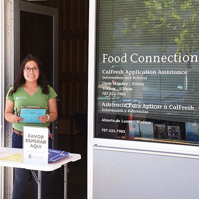 Happy and helpful Redwood Empire Food Bank staff member standing in front of the Food Connections Resource Center 