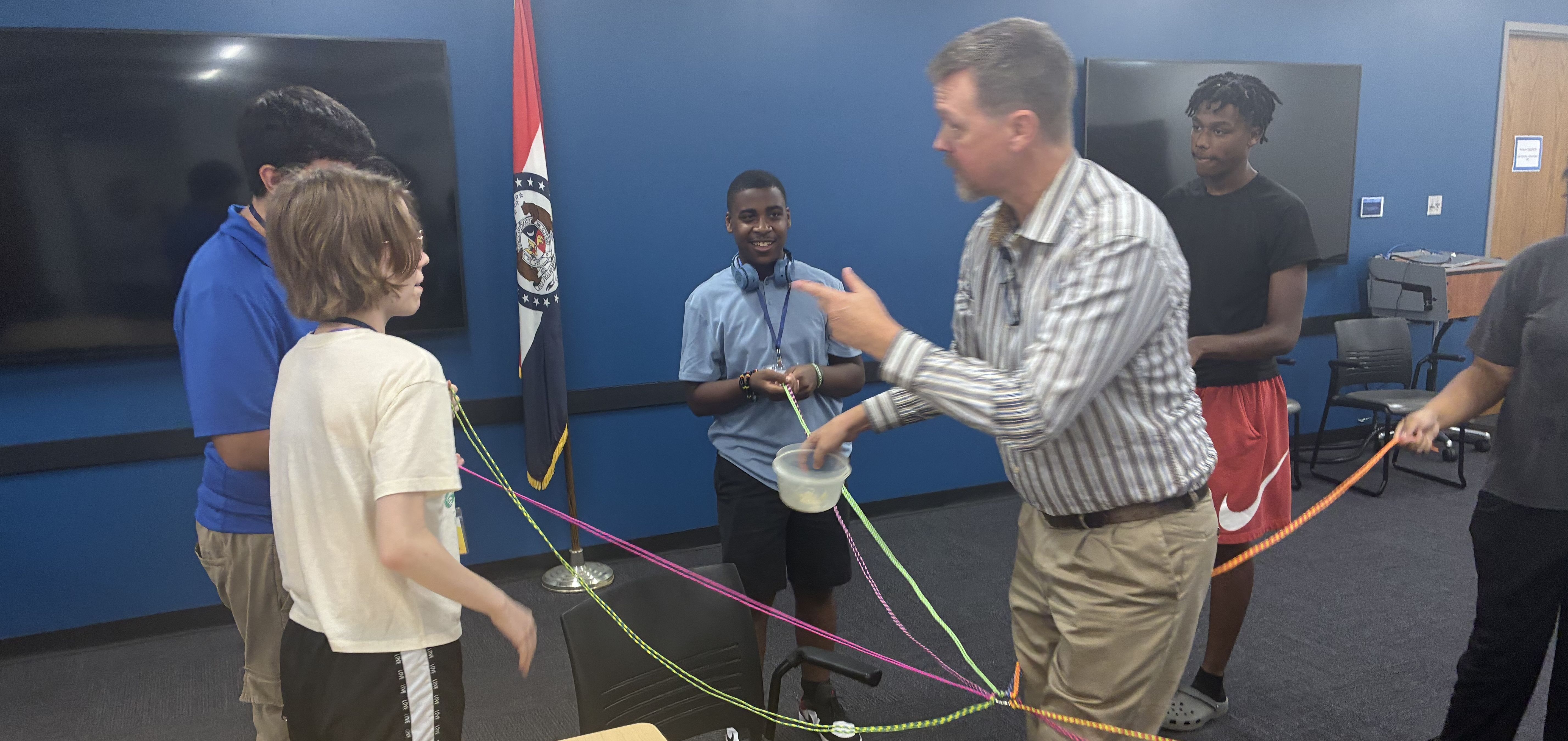 man with kids holding ropes in a classroom