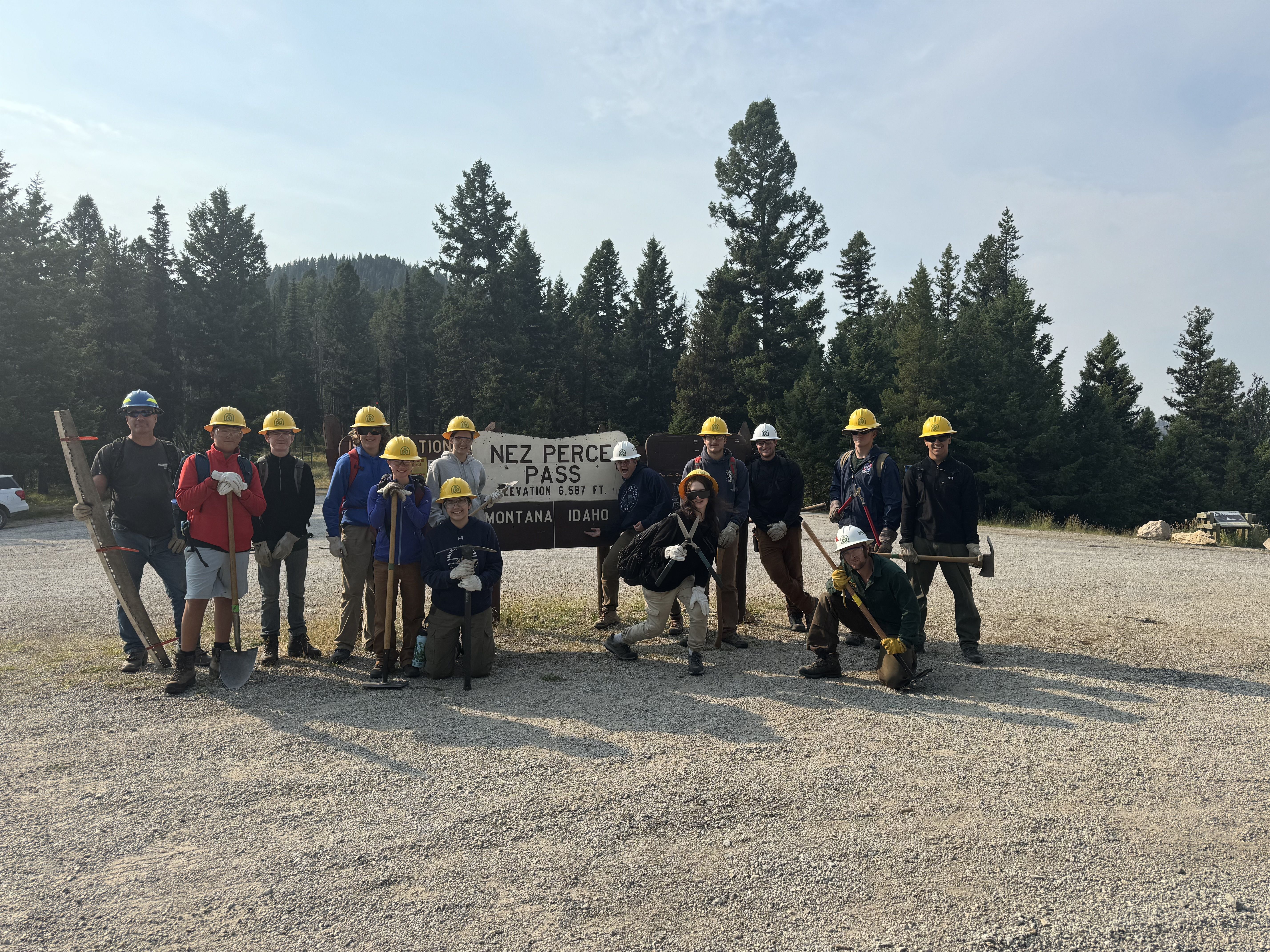 A youth crew stands next to a Bitterroot National Forest sign