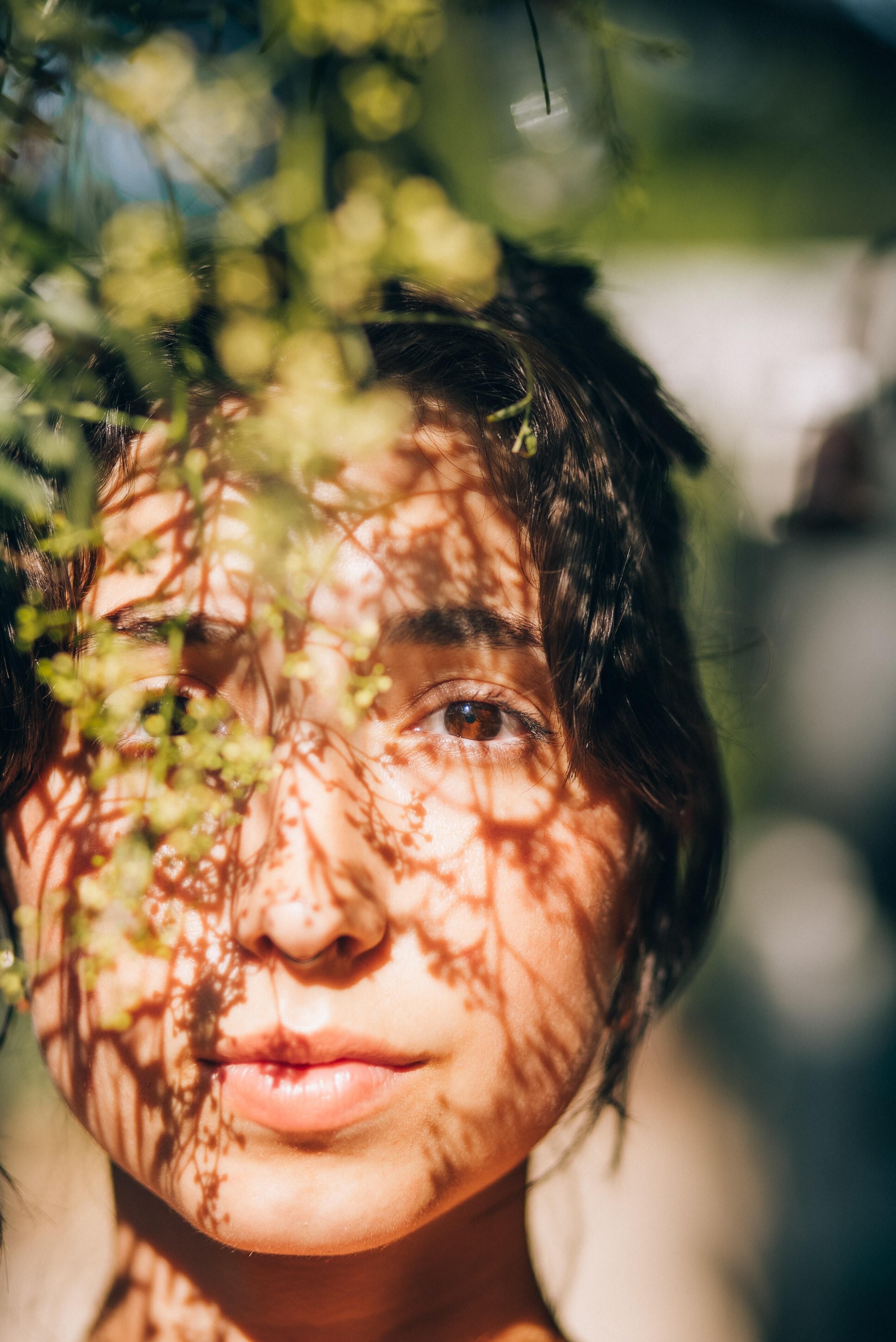 image of shadows of leaves cast on woman's face