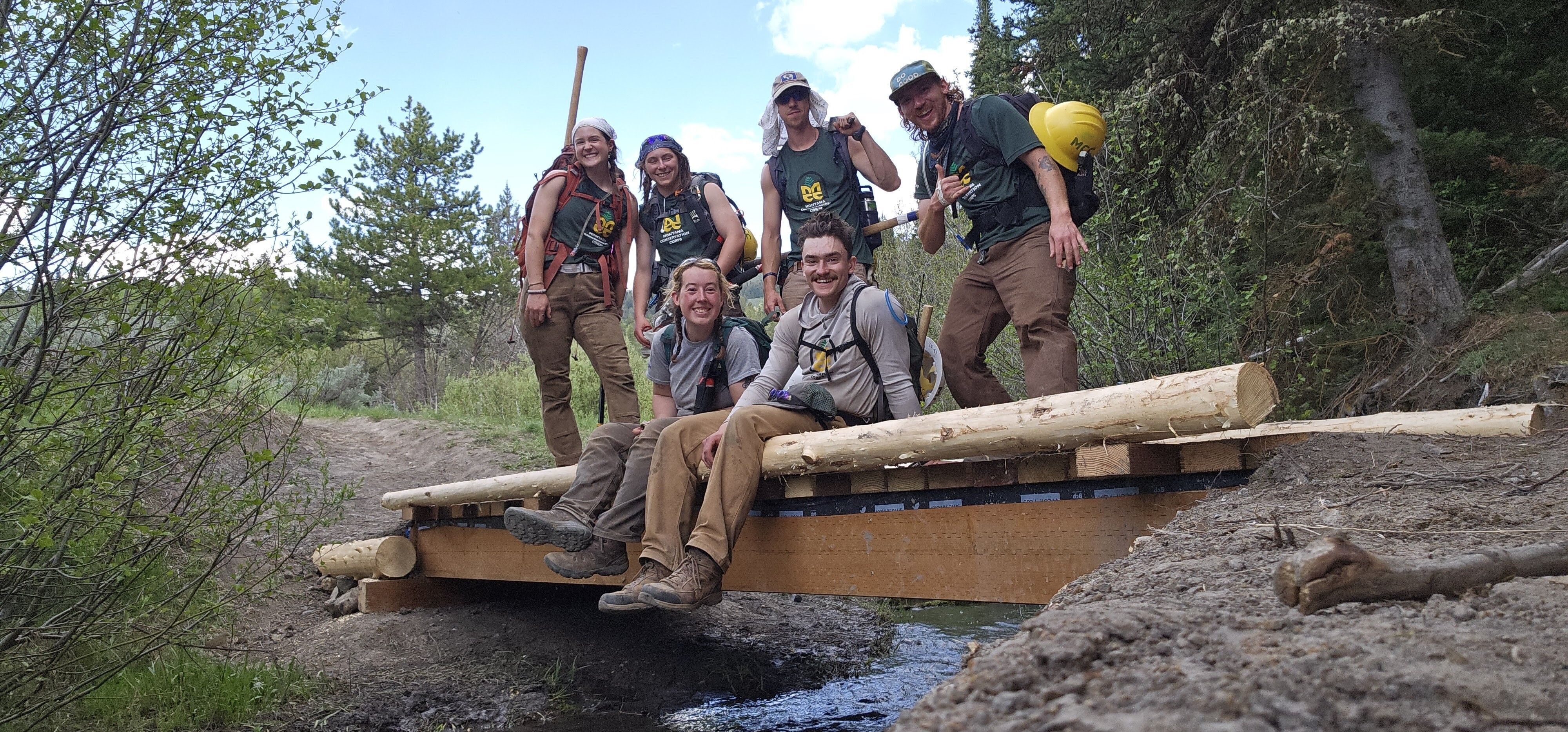 A crew sits smiling on a bridge