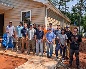 Group of volunteers posing together outside a house under construction