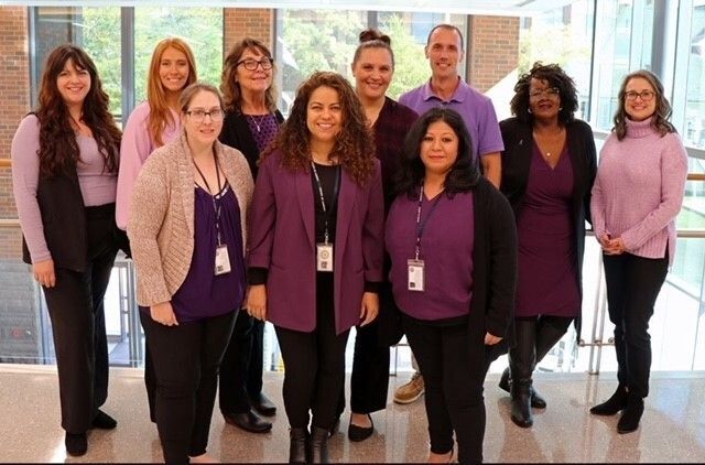 Victim Services pose at the Justice Center wearing purple to show support of domestic violence awareness.