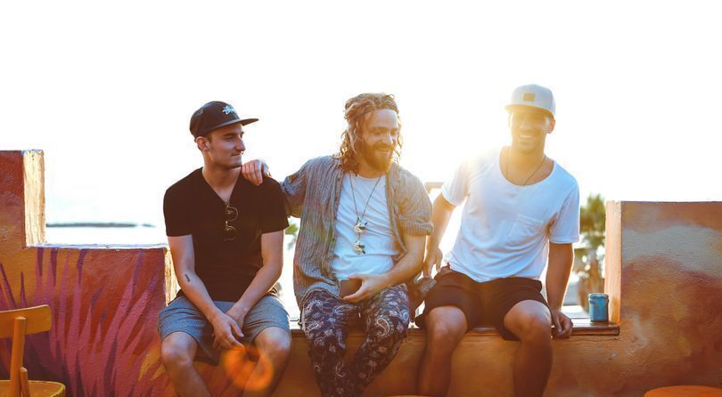 Three young men sitting on a bench enjoying their friendship