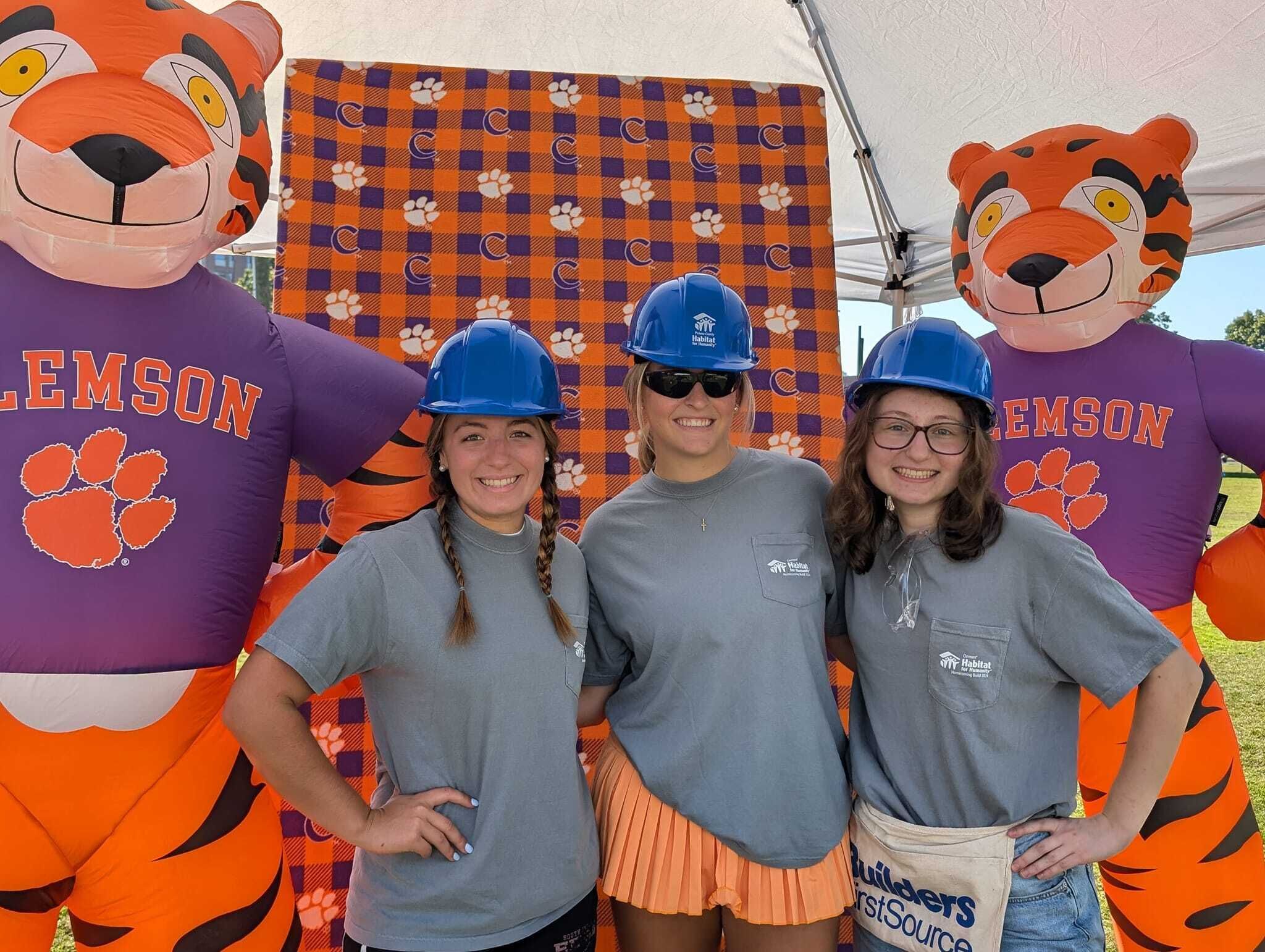 Clemson Campus Chapter students smiling in a group photo on Bowman Field while wearing Habitat for Humanity hard hats.