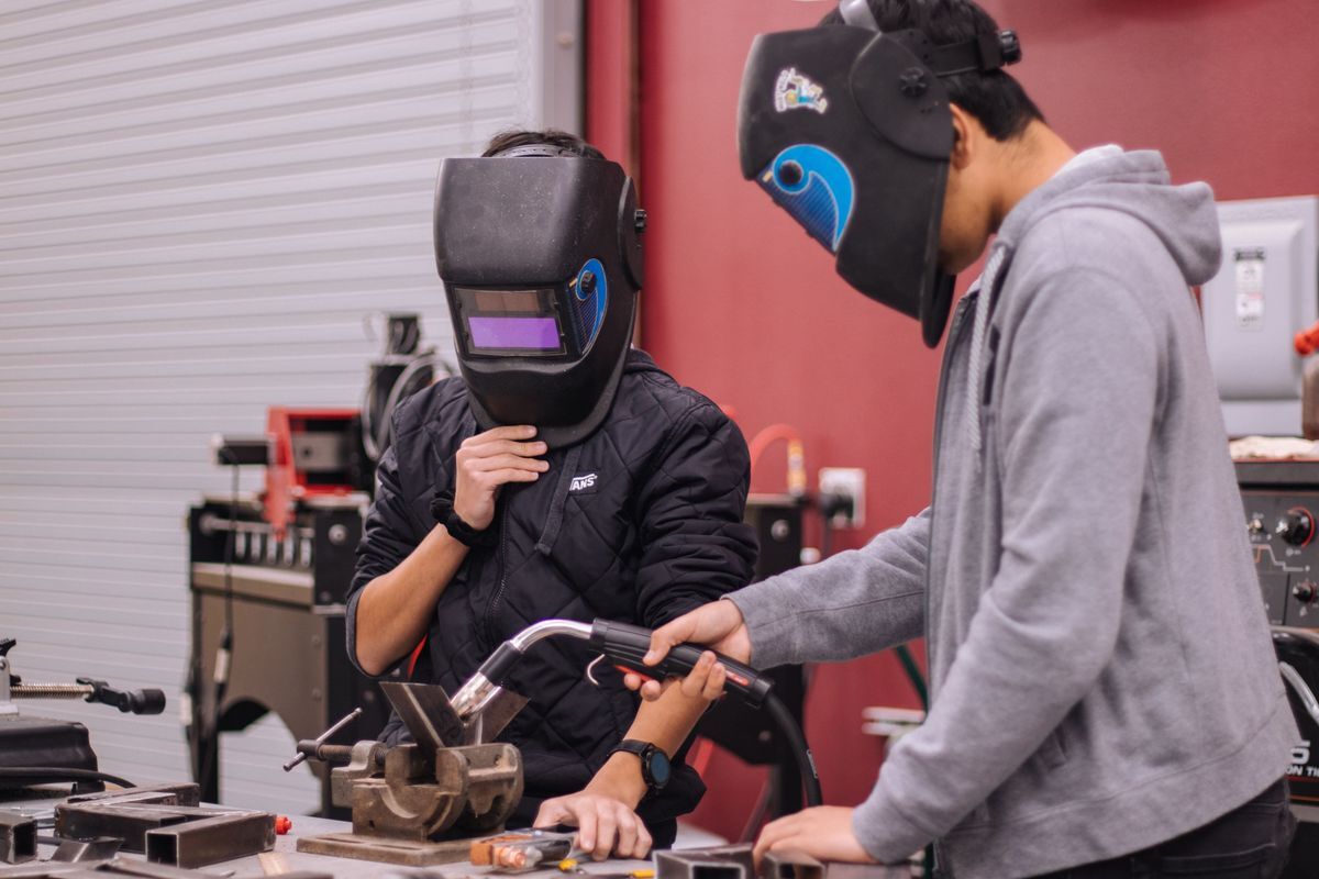 Teens welding in shop class.