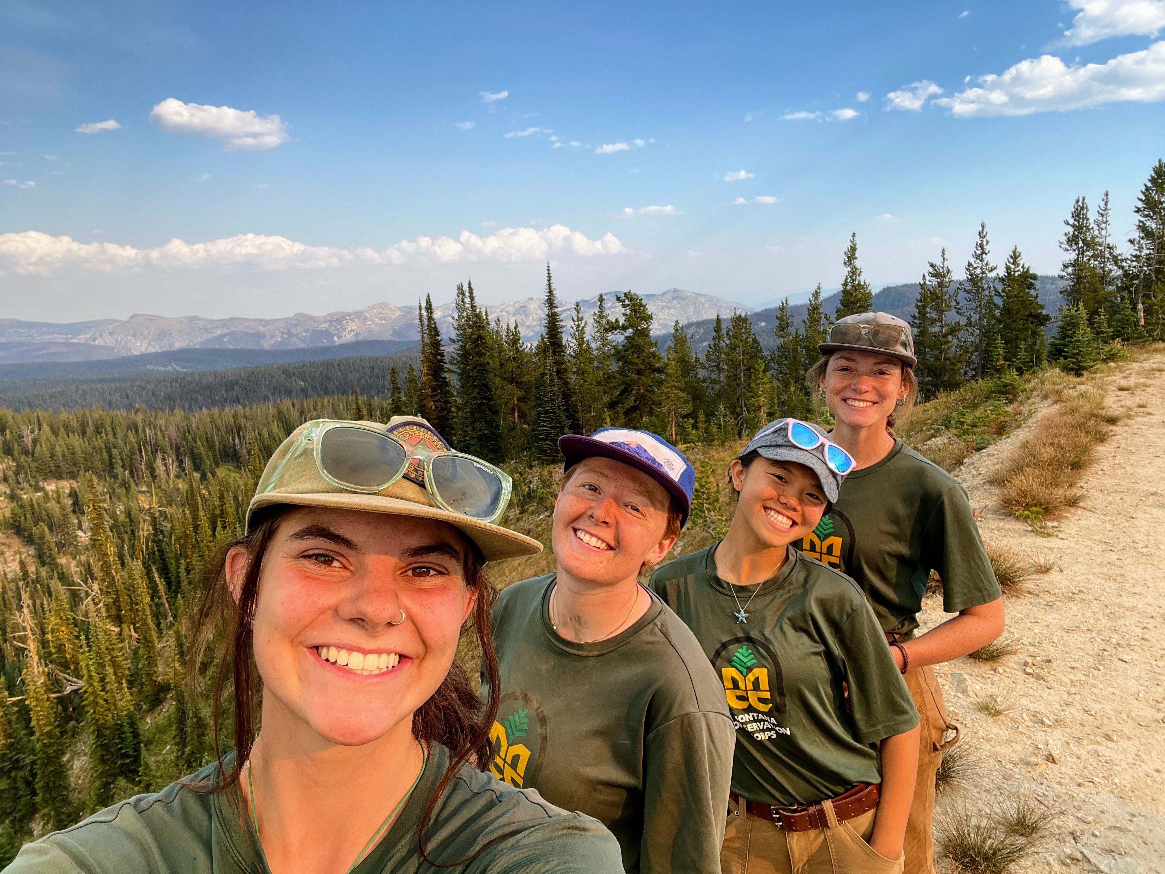 The women's+ crew smiles in a selfie on a mountain ridgeline.