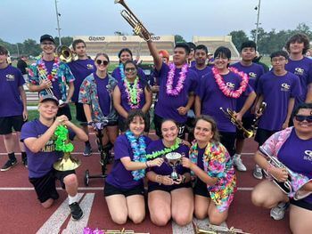 The high brass players pose in a group photo on the track with their “section cup”