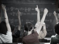 Children in classroom raising their hands