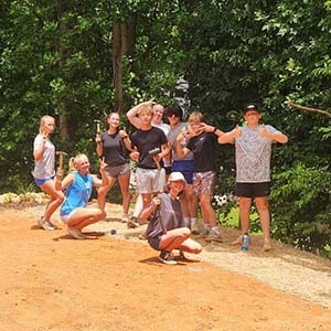 Volunteers carrying buckets and pushing a wheelbarrow along a paver path