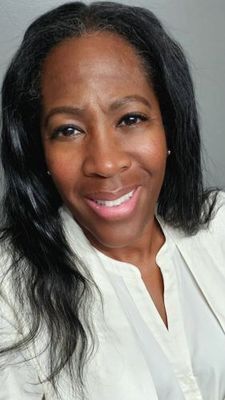 Photograph of brown-skinned woman smiling with black hair, brown eyes