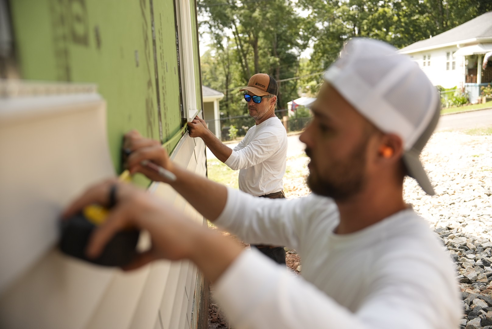 Alair Homes volunteers work to install siding on Ryan St.