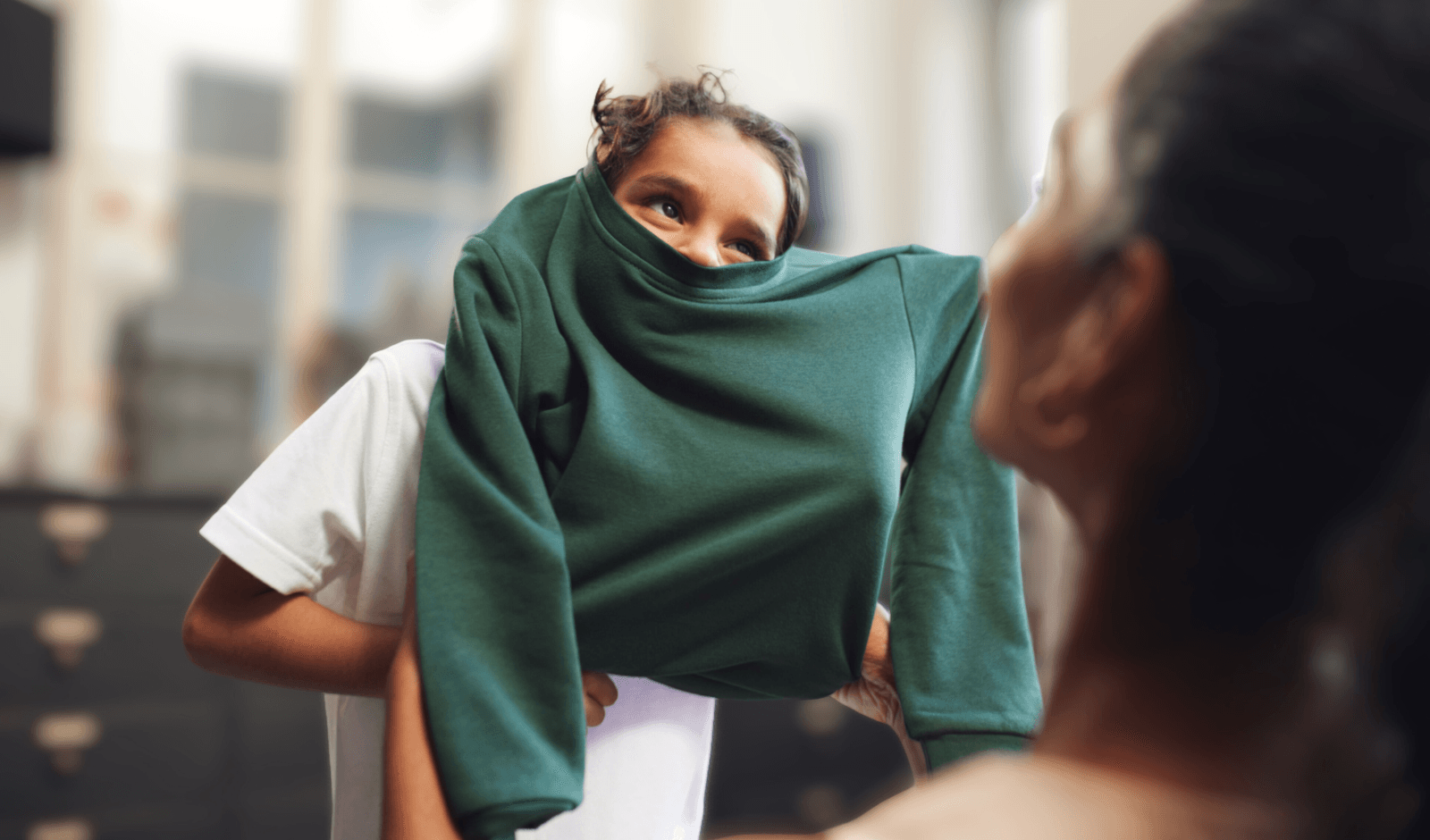 Child putting on green sweater