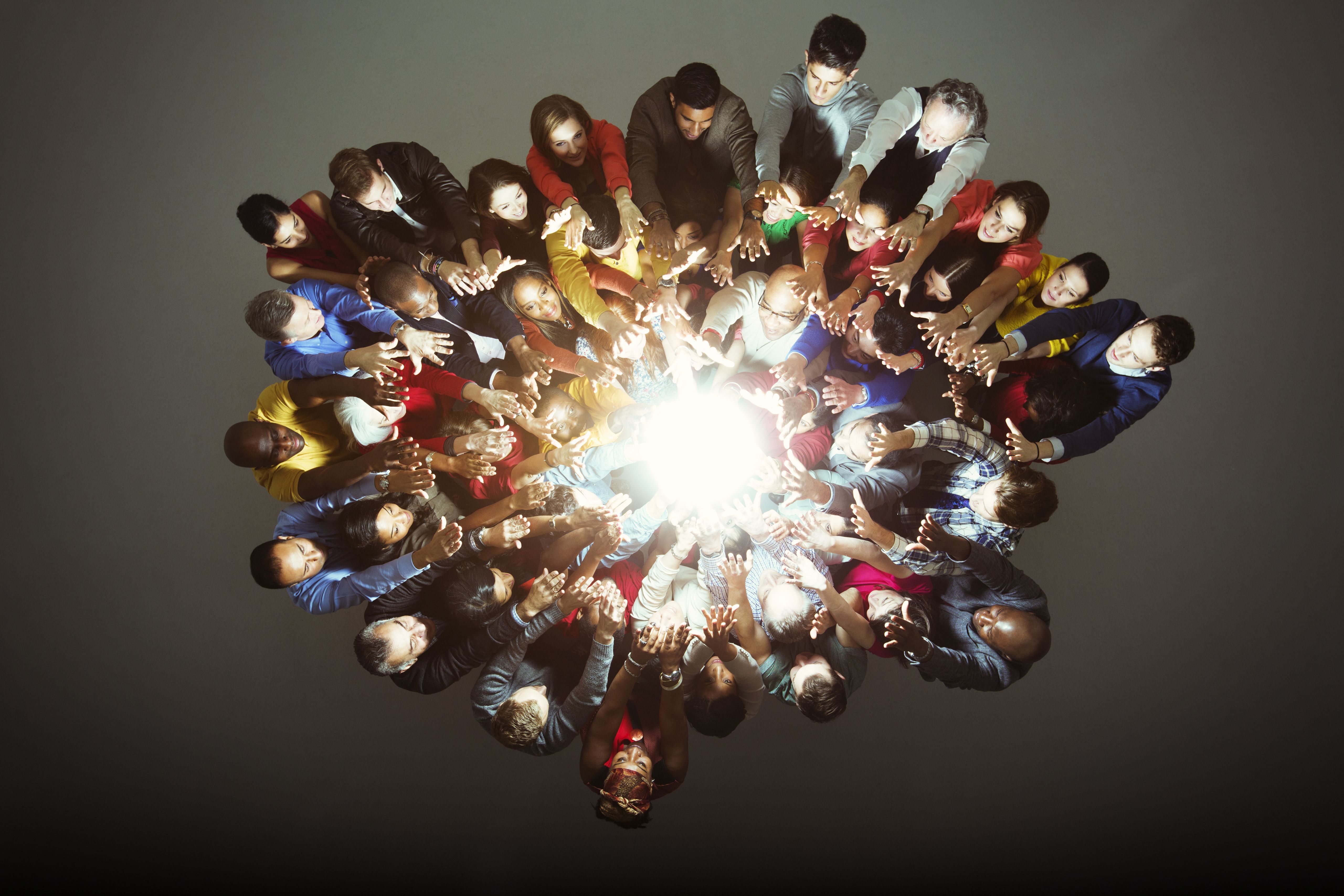 Diverse people gathered a bright light suggestive of the power of collaboration