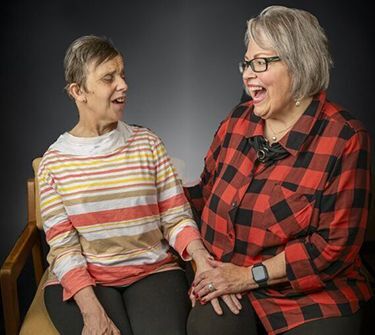 Heather and her caregiver face each other and smile