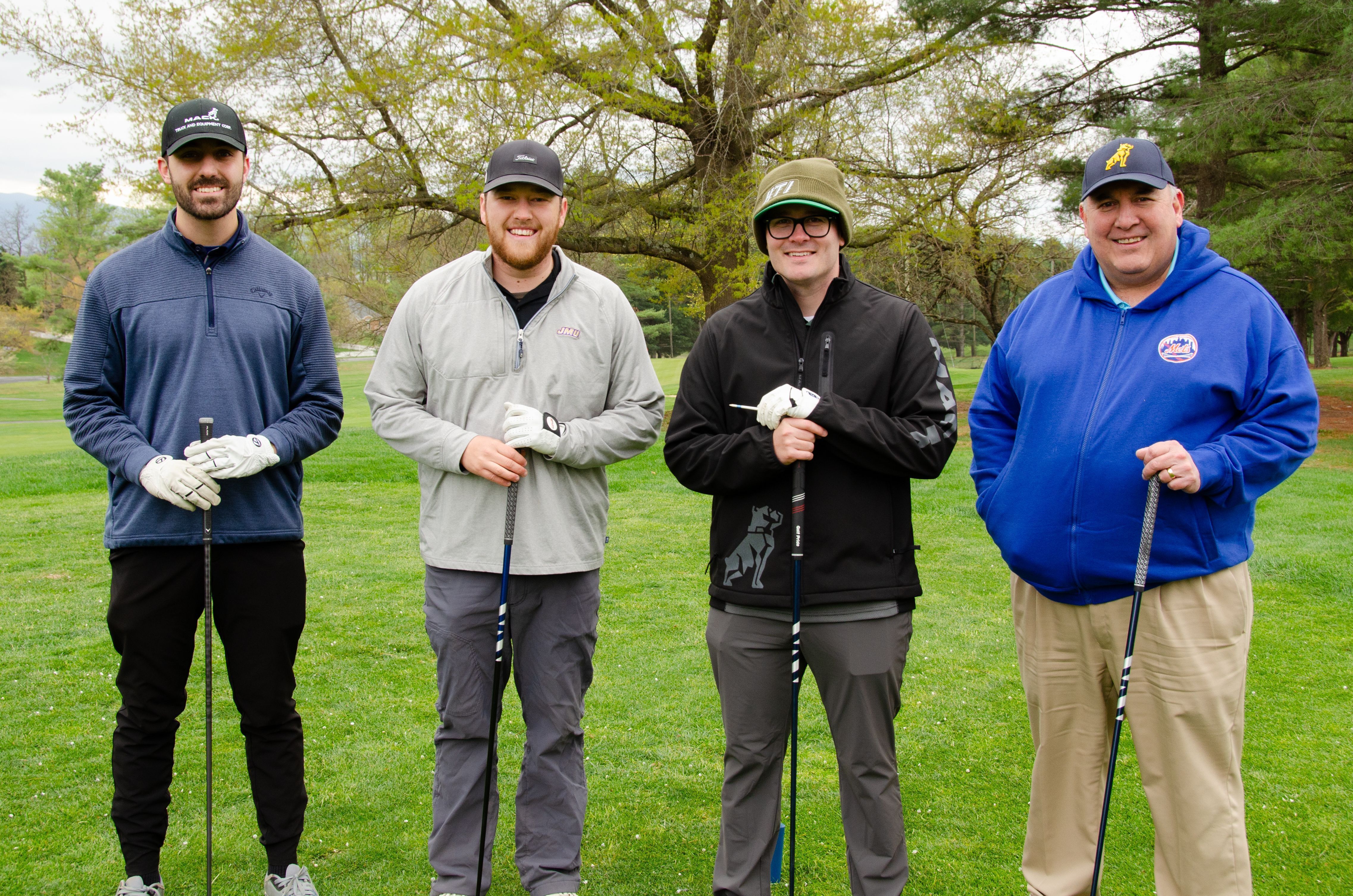 4 Golf players standing holding their clubs