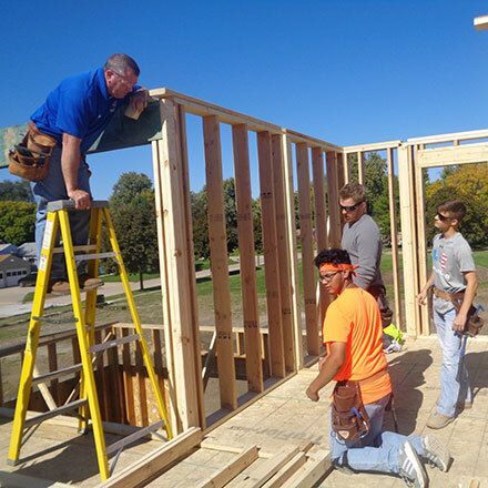 Students listening to instructions on building a house.