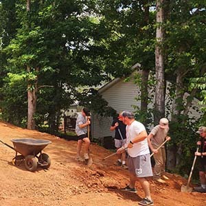 Three volunteers talking near a truck and landscaping tools