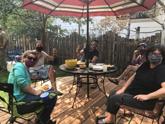 [Image Description: MCC Staff shown having an outdoor meeting, masked up and enjoying time together on a back patio.]