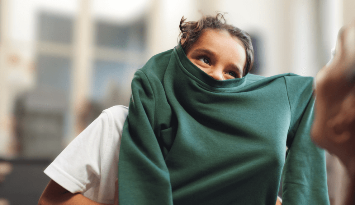 Two girls with pink coats and back packs walking into school. 