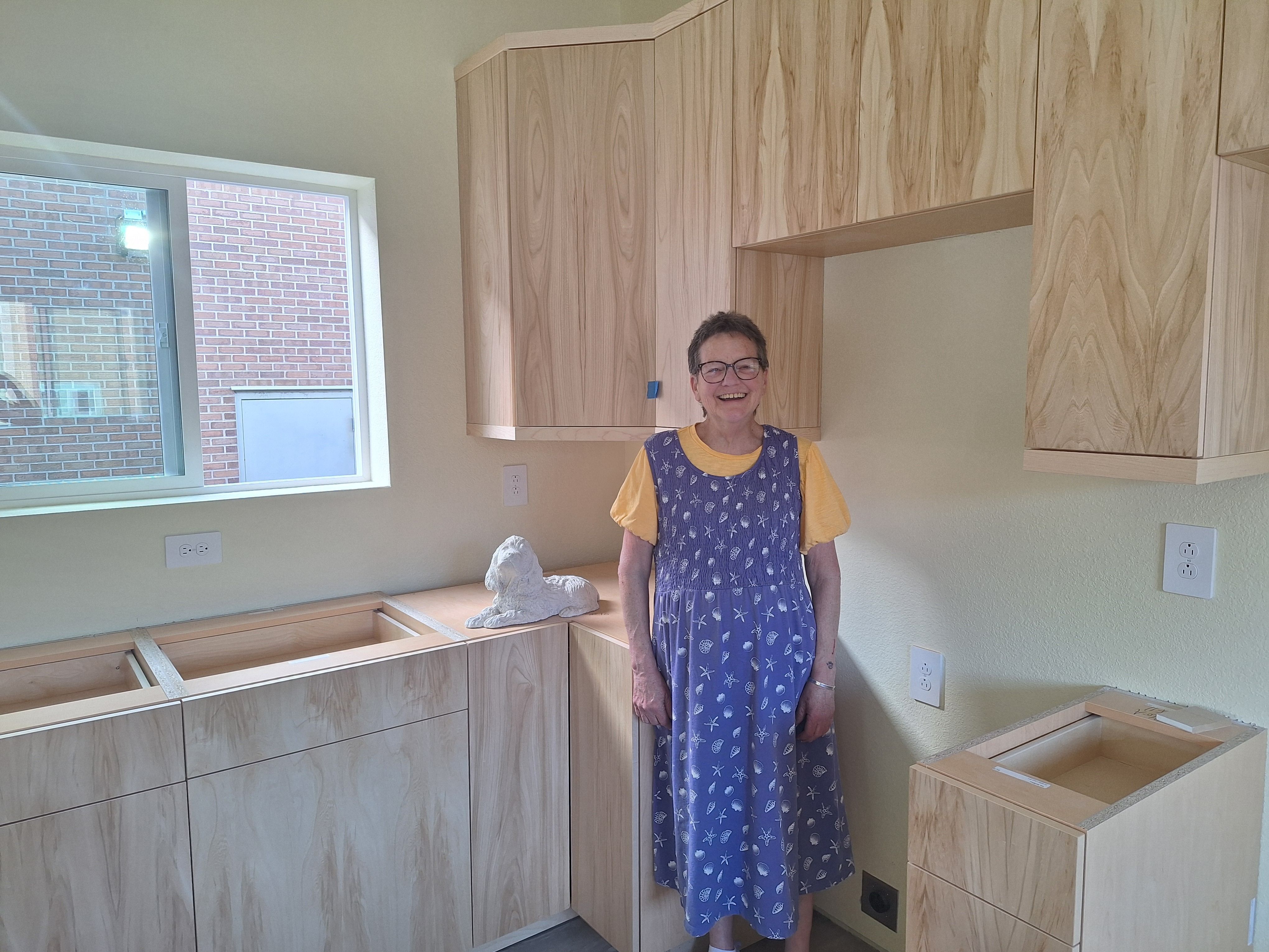 Trilby standing next to her cabinets during construction.