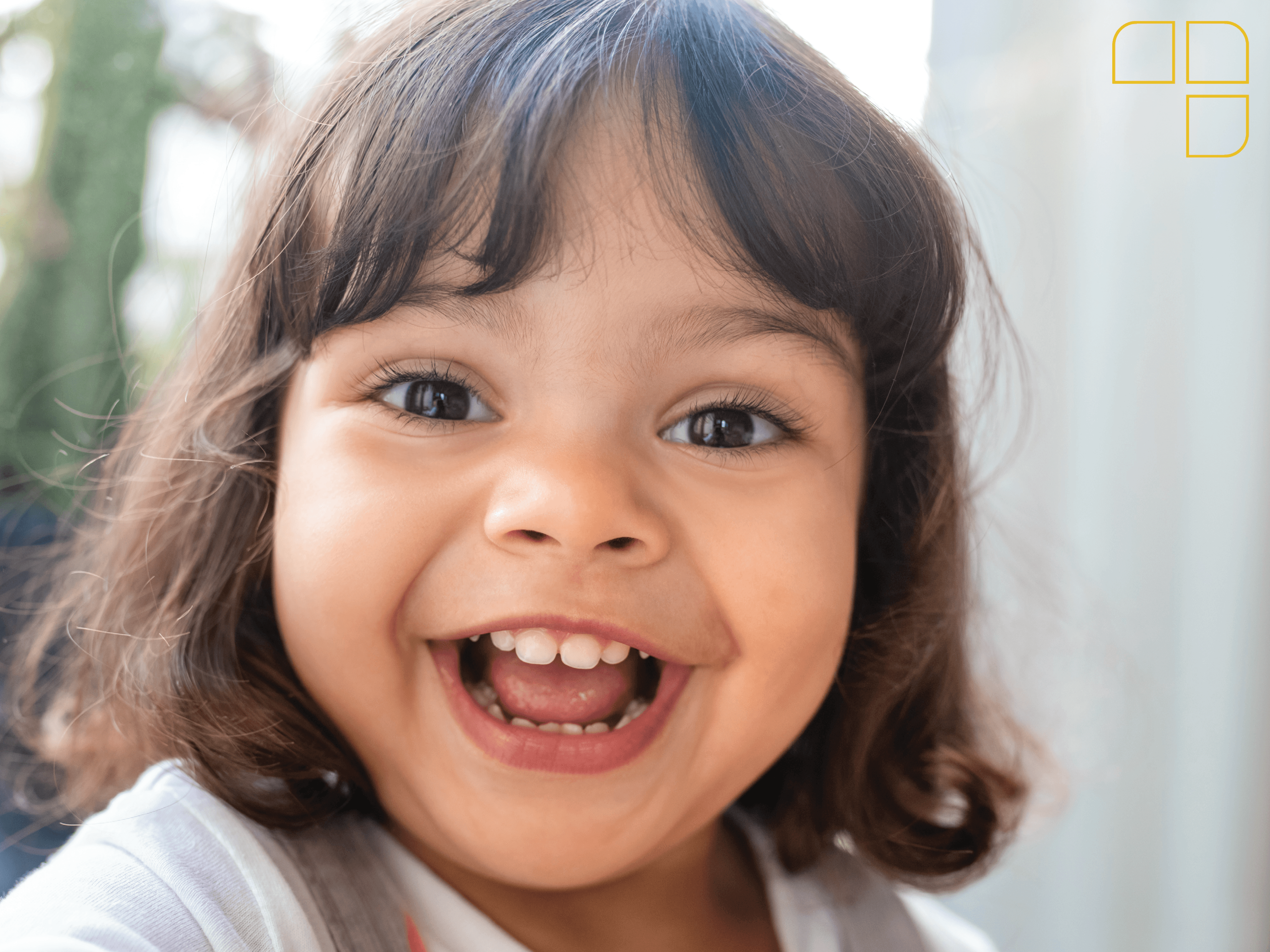 A little girl with short brown hair smiling into the camera