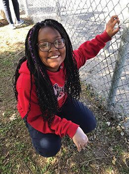 Student standing by a fence.