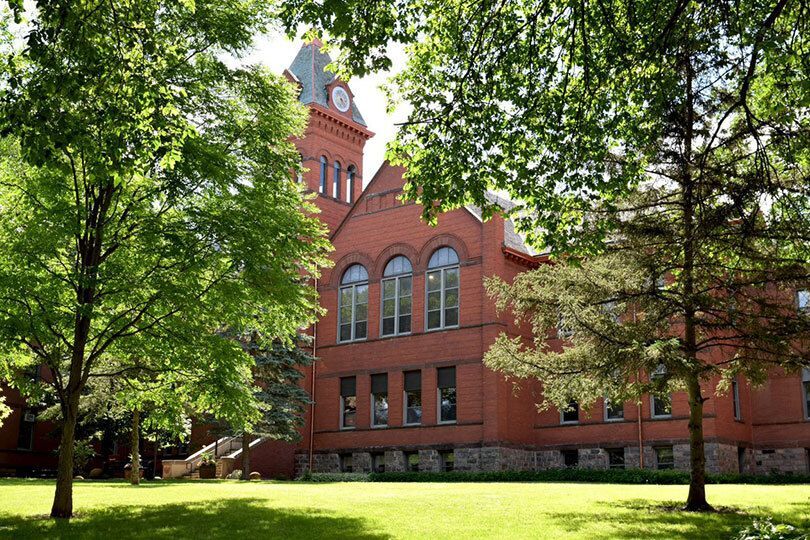 VCSU front lawn with green grass, trees and sun shining on the Clocktower .