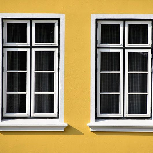 Yellow exterior wall with two windows.