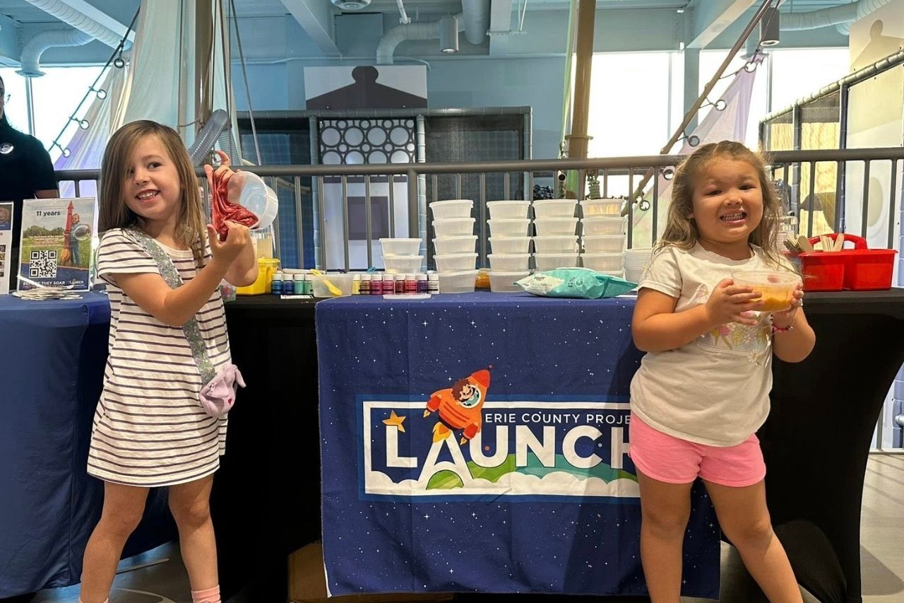 Two school-aged girls posing next to DIY slime