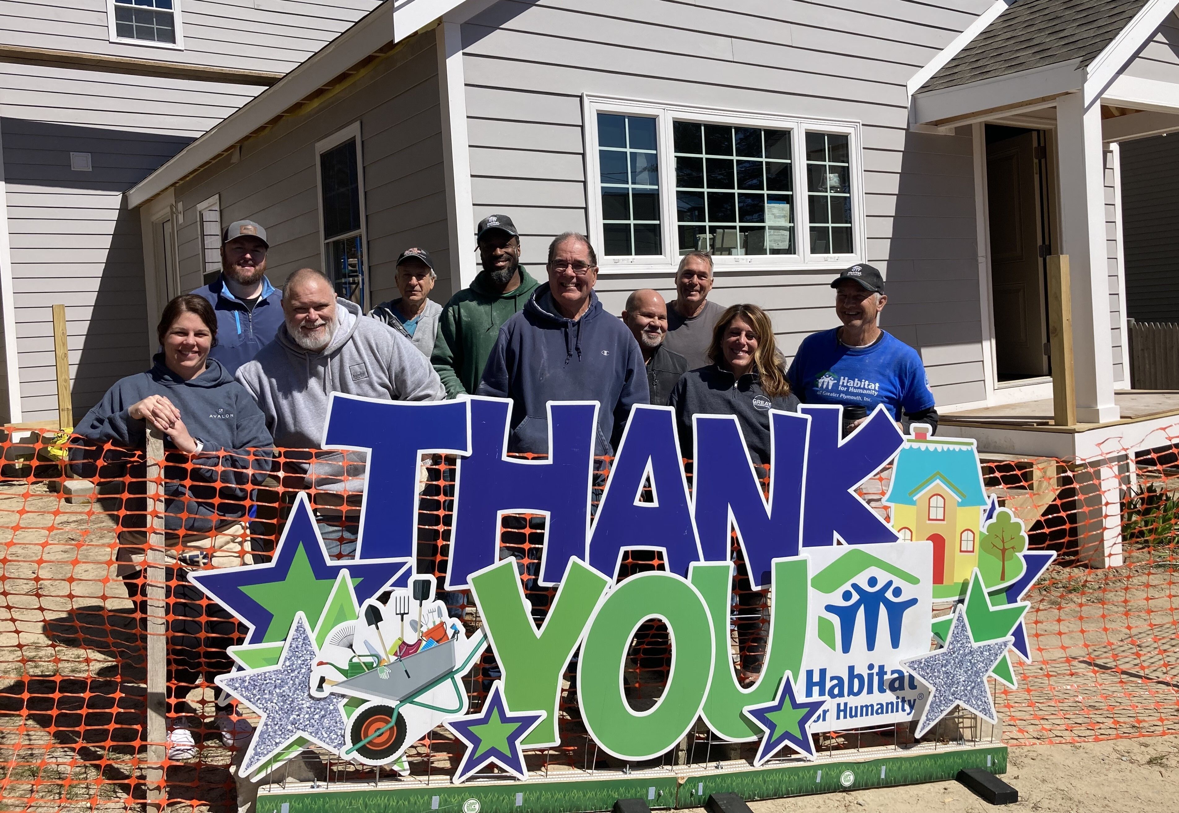 A group of Habitat volunteers with a yard Thank You sign