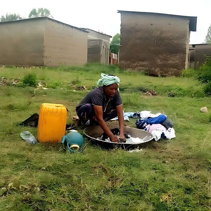 Woman washing clothes in a shallow bowl.