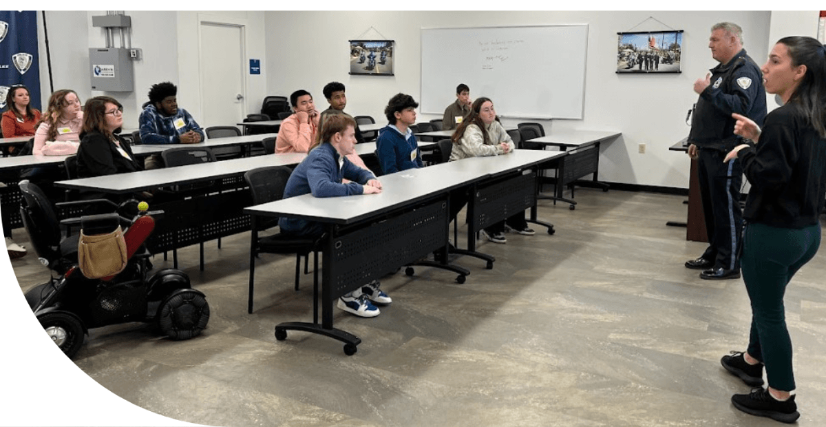 students sitting at tables listening to a police officer