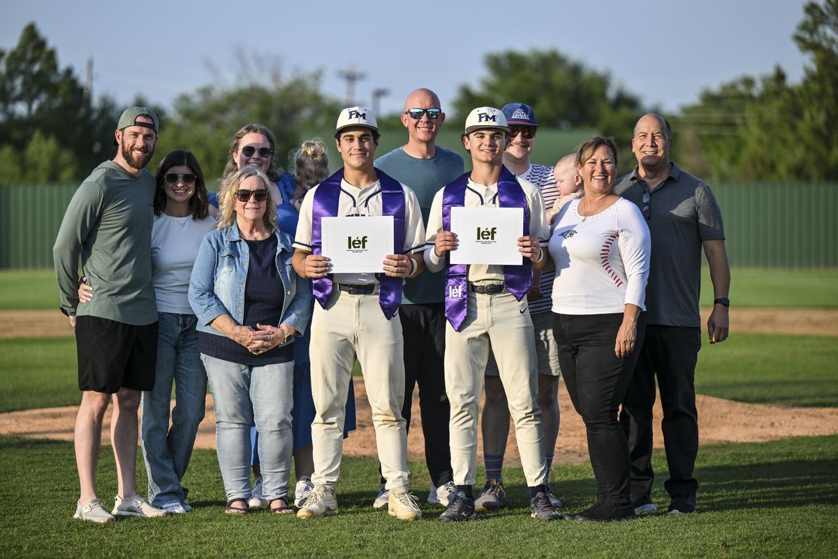 two scholarship recipients in baseball uniforms with donors