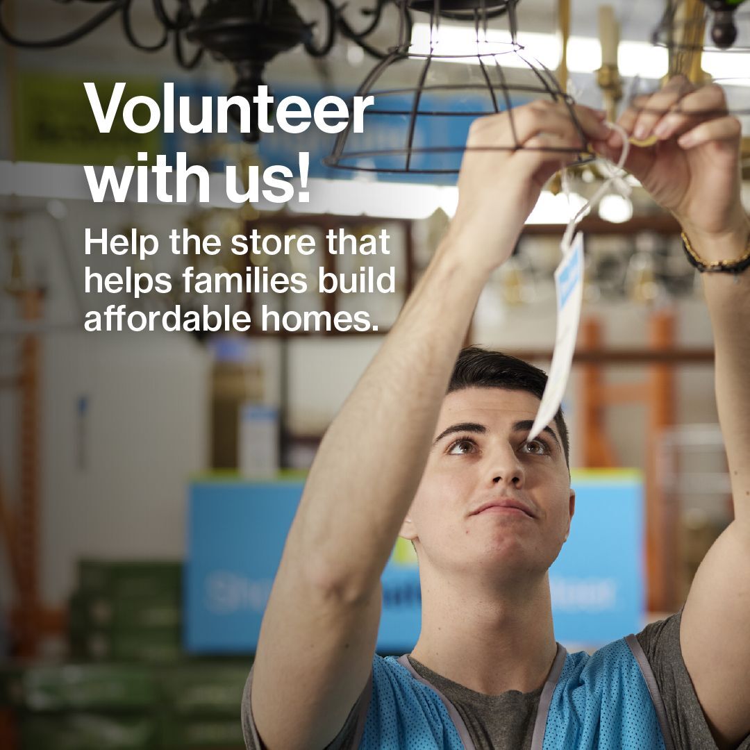 Young male Habitat ReStore volunteer hanging a price tag on a light fixture with text overlay: “Volunteer with us! Help the store that helps families build affordable homes.”