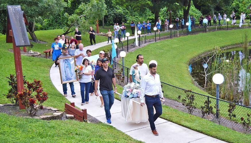 Images of the Virgin Mary are carried around Emmanuel Parish's lake as the faithful pray the rosary following the Steps for Life Mass