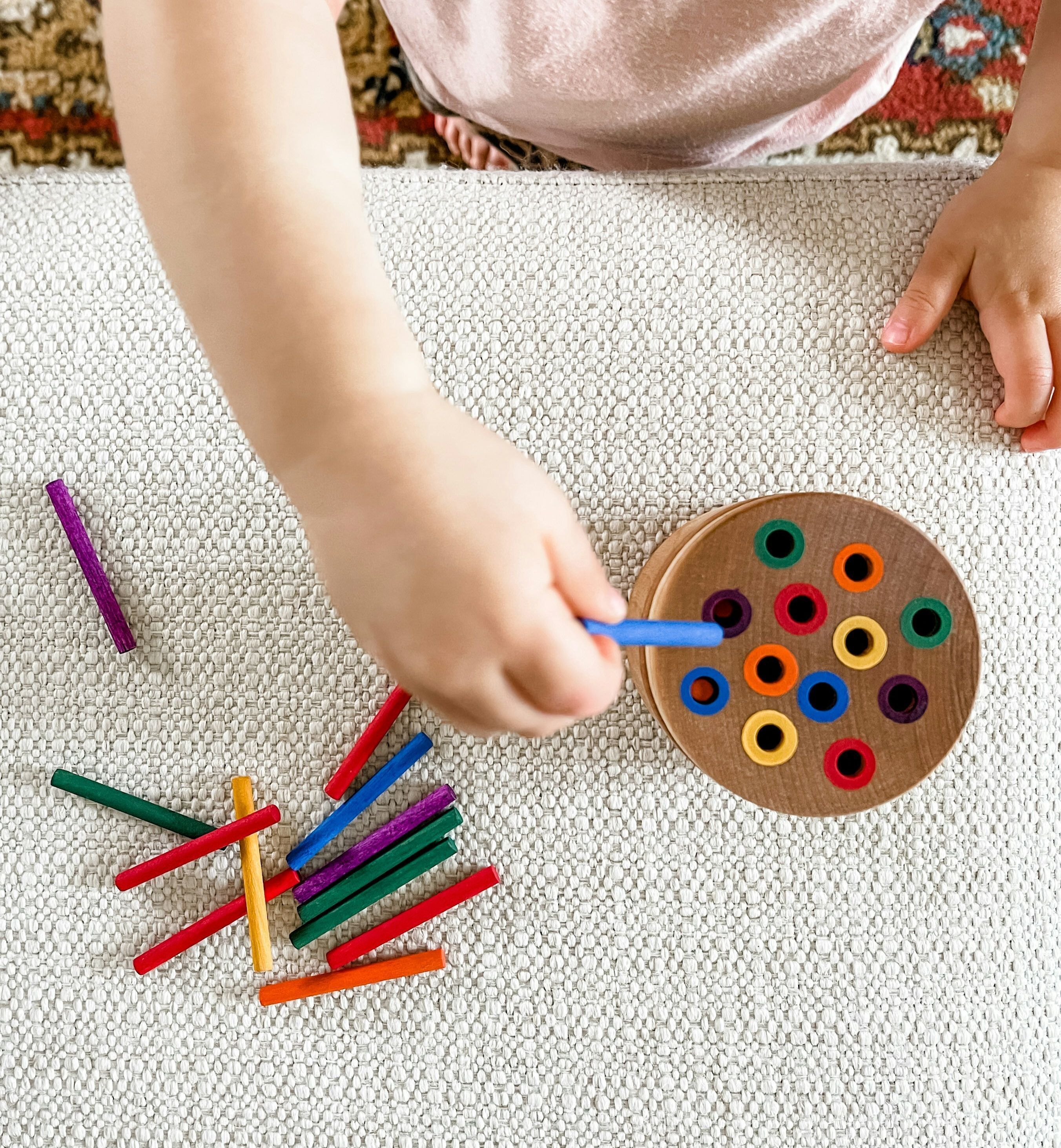 A child using crayons to color. The image only shows the child's hands. 