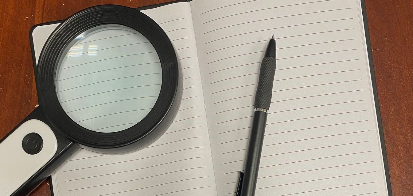 Open blank notebook with magnifying glass and pen.