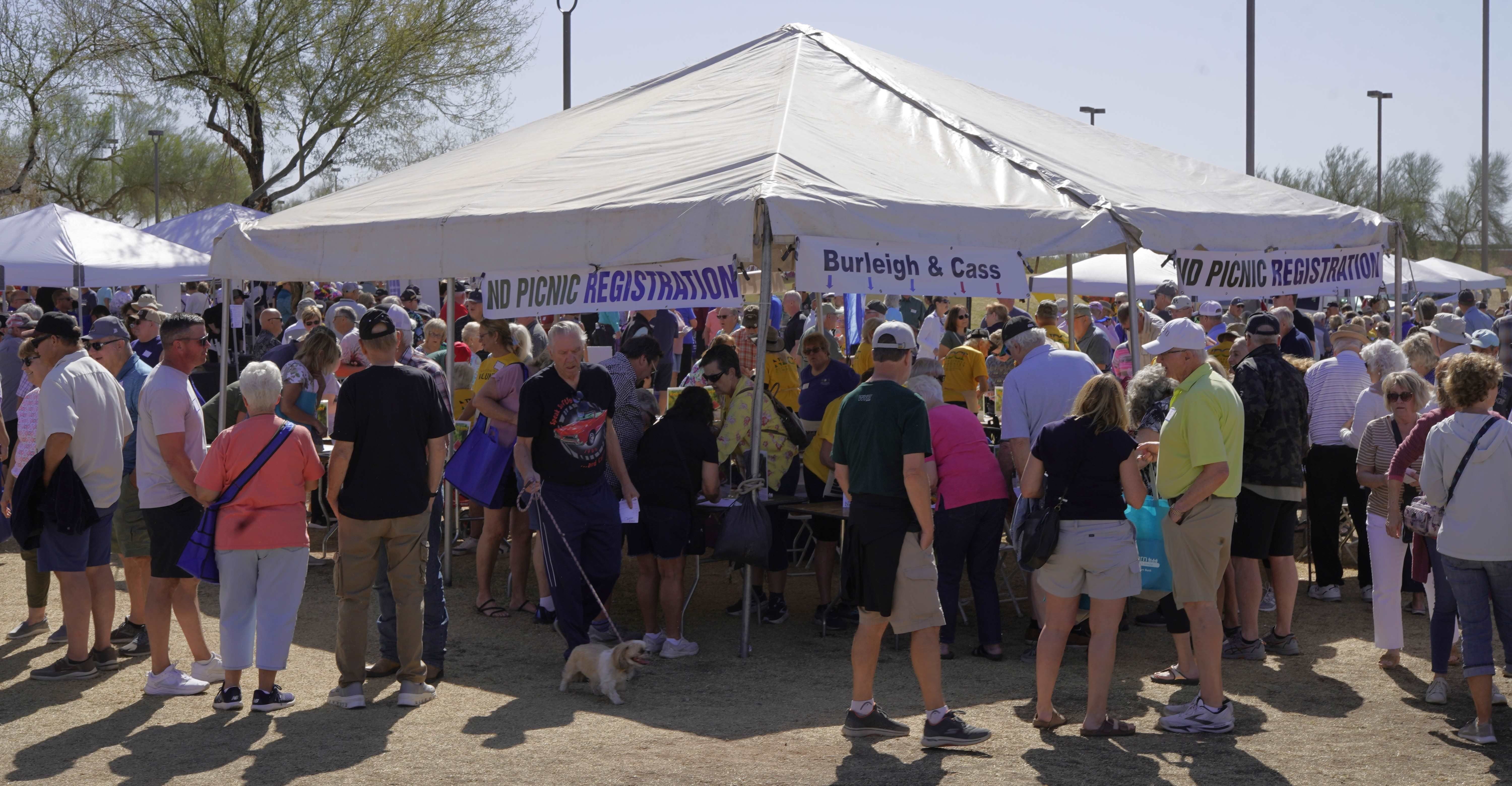 A photo of the registration booth at the 2025 ND Picnic in AZ with many people signing up by the ND County they lived in.